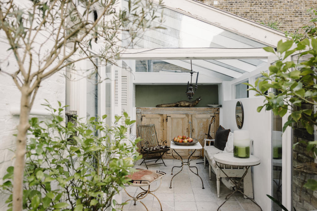 The glass-roofed garden conservatory treatment room at Cotherstone House, with sage green walls and natural light
